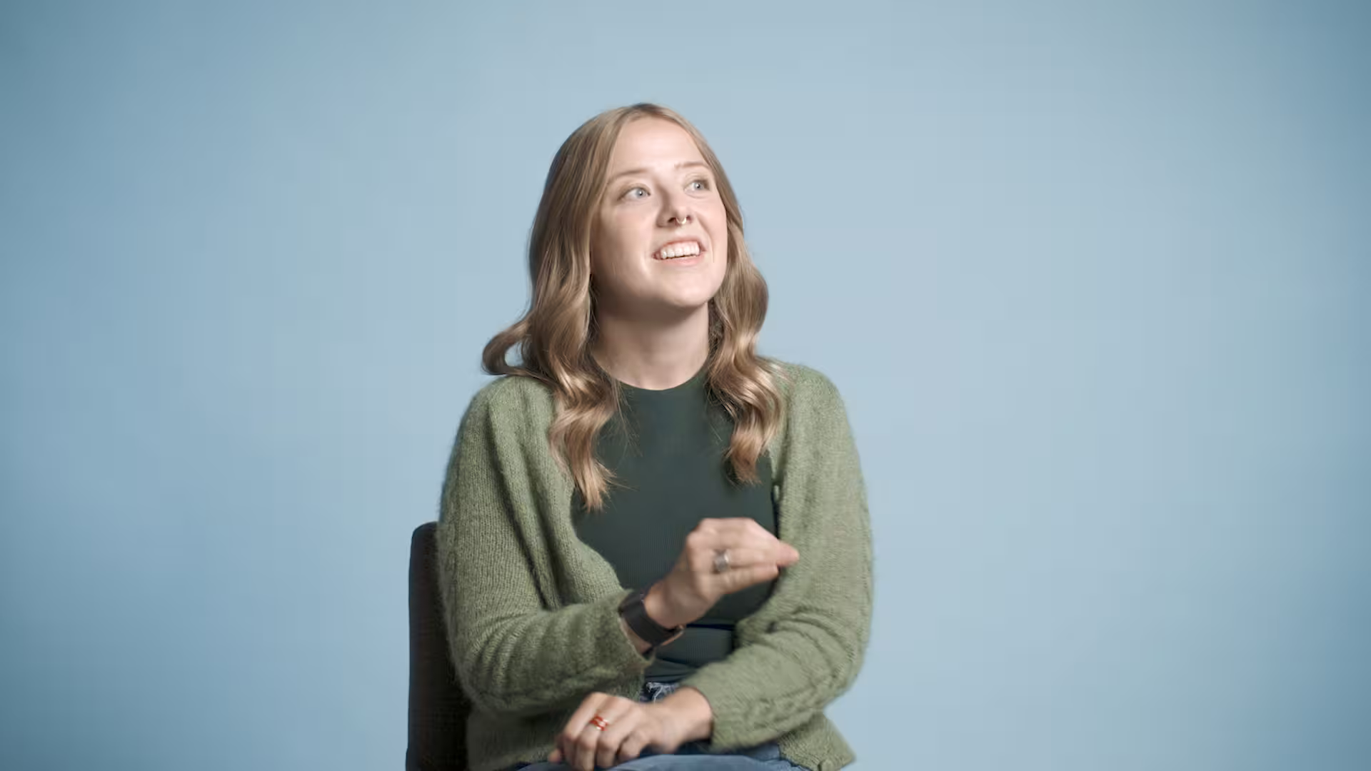 Smiling young woman looking upward against a light blue background